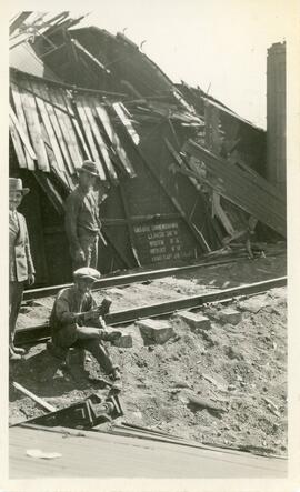 Three Men In Front of Train Wreckage