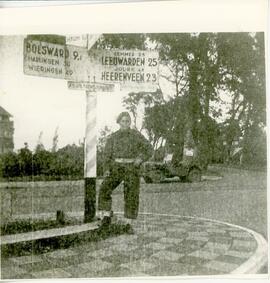 Soldier Len Martin posing under road sign in the Netherlands