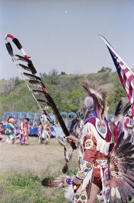 Henry Beaudry in traditional regalia bearing a sacred eagle staff while leading the ceremonial pr...