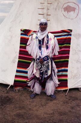 Grass dancer standing in front of tipi