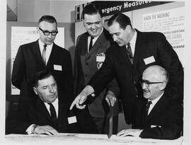 5 men in front of Emergency Measures sign