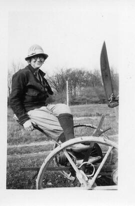 Unidentified woman seated on a horse drawn hay mower